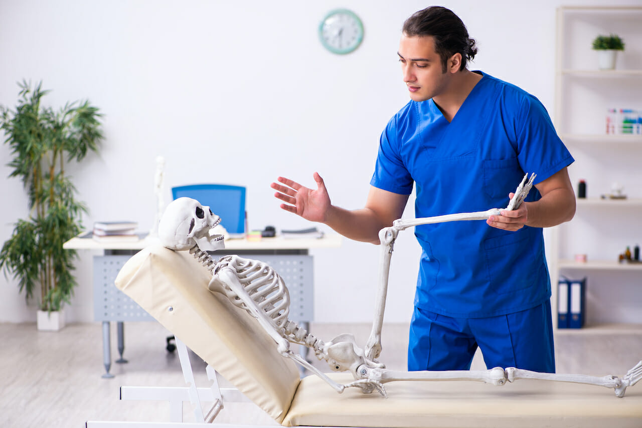 Young male doctor and skeleton on the couch